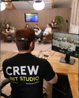 Unit Studio crew member at the production desk, monitoring a multi-camera recording of a panel discussion