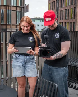 Two Unit Studio crew members reviewing footage on a tablet and camera during a rooftop shoot